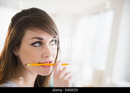 Jeune femme tenant un crayon dans sa bouche Banque D'Images
