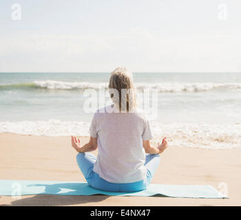 USA, Floride, Jupiter, Senior woman practicing yoga on beach Banque D'Images