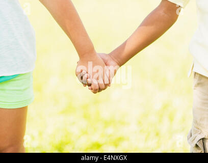 Girl (12-13) and boy (6-7) Holding Hands, Close up Banque D'Images