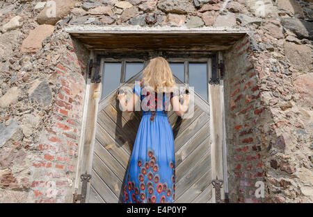 Vue arrière de femme avec robe bleue à l'entrée de porte ancienne Old Manor Banque D'Images