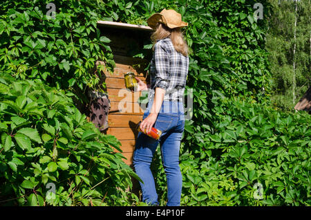 Farmer woman with hat à pied à la porte de la chambre sous-sol cave en milieu rural avec la conservation des aliments en conserve bocaux pots. Banque D'Images