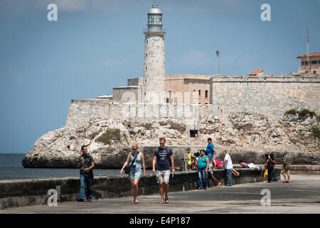 Les touristes et les habitants de marcher sur le Malécon avec Castillo de los Tres Reyes Magos del Morro en arrière-plan, La Havane, Cuba Banque D'Images
