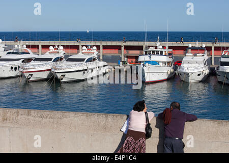 Mature couple regardant luxury yachts amarrés au port Olympique de Barcelone, Catalogne, Espagne. Banque D'Images