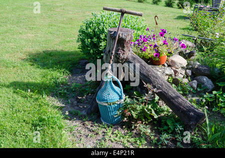 Grande bouteille de vin emballé dans des branches en plastique bleu et grand fer stylisé herbe fleurs près de l'ouvreur Banque D'Images