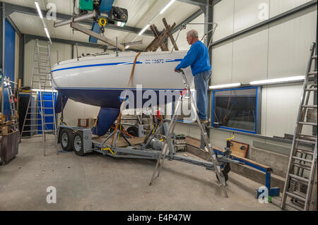 Un homme travaillant sur un bateau à voile dans un atelier Banque D'Images