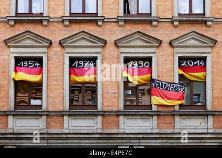 L'Allemagne Championne du Monde de Football 1954 1974 1990 et 2014 ; avec des drapeaux de l'année dates au fenêtres d'une fan allemande Banque D'Images