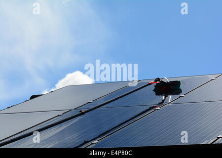 Des panneaux solaires sur une propriété résidentielle sont nettoyés à l'aide d'une grande portée et de l'eau de lavage pôle nourris Banque D'Images