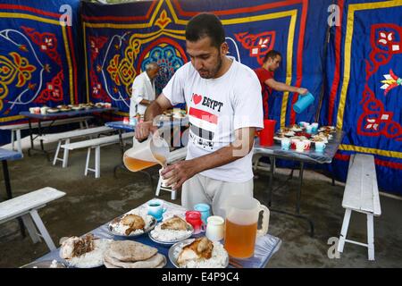 Le Caire, Égypte. 15 juillet, 2014. Un homme prépare des repas pour un banquet de bienfaisance au Caire, Égypte, le 15 juillet 2014. La charité des banquets, ou ma'idat al-Rahman, représentent une longue tradition du Ramadan en Egypte, par lequel riches patrons fournissent leurs moins riches coreligionnaires avec les repas pour rompre le jeûne. © Cui Xinyu/Xinhua/Alamy Live News Banque D'Images