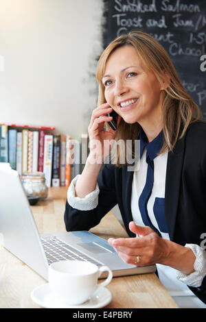 Businesswoman Talking On Mobile Phone In Cafe Banque D'Images