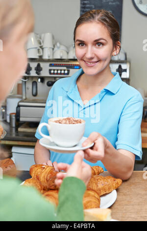 Serveuse dans Café servant du café avec la clientèle Banque D'Images