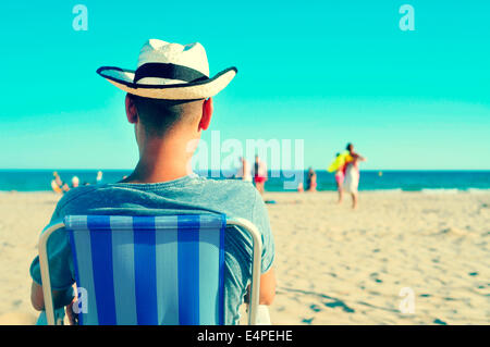 Un jeune homme avec un chapeau de paille se détendre sur la plage Banque D'Images