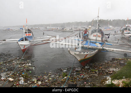 La province de Cavite, Philippines. 16 juillet, 2014. Les pêcheurs essayer de s'assurer de leur bateau qu'ils bravent les vents forts de typhon Rammasun dans la province de Cavite, Philippines, le 16 juillet 2014. Au moins 5 personnes ont été tuées à la suite de l'assaut du typhon Rammasun (nom local : Glenda) qui a paralysé la capitale des Philippines, de Manille, mercredi. Credit : Rouelle Umali/Xinhua/Alamy Live News Banque D'Images