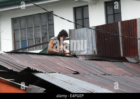 La province de Cavite, Philippines. 16 juillet, 2014. Un homme fixe le toit de sa maison à partir de la des vents violents apportés par le typhon Rammasun dans la province de Cavite, Philippines, le 16 juillet 2014. Au moins 5 personnes ont été tuées à la suite de l'assaut du typhon Rammasun (nom local : Glenda) qui a paralysé la capitale des Philippines, de Manille, mercredi. Credit : Rouelle Umali/Xinhua/Alamy Live News Banque D'Images