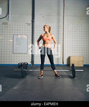 Fit young woman standing at sport avec barbell sur parole. Fort et musclé au sport. femelle crossfit Banque D'Images