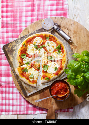 Pizza garnie de sauce tomate, de mozzarella et de feuilles de basilic Banque D'Images