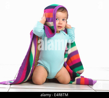 Bébé garçon avec couverture à rayures colorées sur la tête Banque D'Images