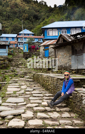 Au Népal, Pokhara, Ghorepani, femme au repos à côté de chemin de pierre walker dans village Banque D'Images