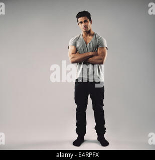 Full Length portrait of muscular young man standing avec ses bras croisés. Modèle hispanique mate dans les occasionnels avec l'exemplaire de l'espace. Banque D'Images