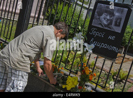 Kiev, Ukraine. 16 juillet, 2014. Un homme jette des fleurs sous le portrait de Valeriya Novodvorskaya avec l'inscription 'héros ne font pas mourir' accroché sur la clôture de l'ambassade russe à Kiev. Les gens apportent des fleurs à l'ambassade de Russie et allumé les bougies à la mémoire des victimes de l'accident de métro de Moscou et la mort de Valeriya Novodvorskaya. Credit : PACIFIC PRESS/Alamy Live News Banque D'Images