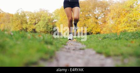 La section basse image de jeune femme tournant les jambes en parc. Athlète féminin du jogging dans un parc un jour d'été. Banque D'Images