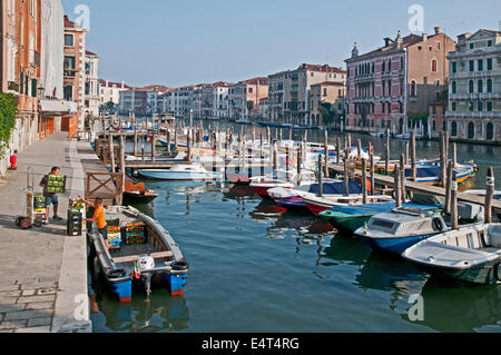 Les hommes loading des légumes frais et fruits sur bateau à moteur du marché du Rialto Venise Italie avec Grand Canal et jetée d'amarrage Banque D'Images