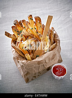 Frites assaisonnées en sac de papier avec du ketchup et de la fourche, Studio Shot Banque D'Images