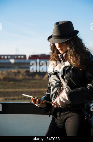 Teenage Girl standing outdoors, le port de Fedora et using tablet computer, Allemagne Banque D'Images