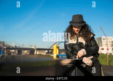 Teenage Girl standing outdoors, le port de Fedora et using tablet computer, Allemagne Banque D'Images