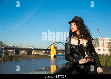 Teenage Girl standing outdoors, le port de Fedora et holding tablet computer, Allemagne Banque D'Images