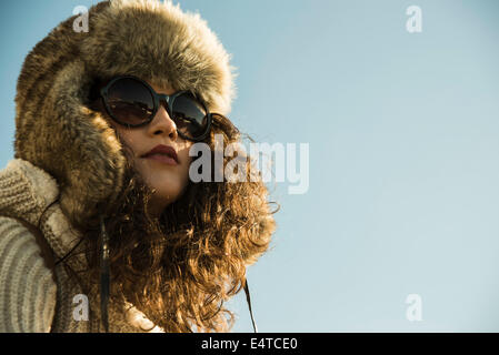 Close-up portrait of teenage girl à l'extérieur, le port de lunettes de soleil et chapeau de trappeur, Allemagne Banque D'Images