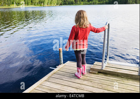 3 ans, fille en chemise rouge sur le quai en bois à la recherche d'un lac, la Suède Banque D'Images