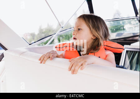 Close-up de 3 ans, fille en gilet orange sur un bateau à moteur, la Suède Banque D'Images