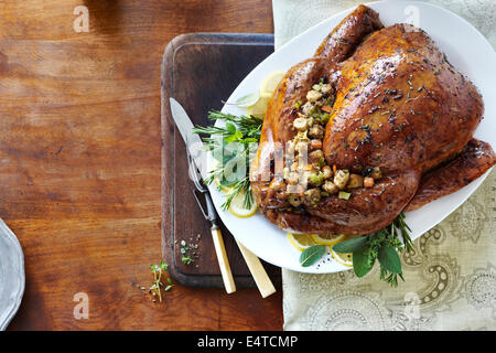 Maison de vacances Turquie entier cuit avec le glaçage, des herbes, et de la farce sur les fines herbes et les citrons sur un plateau avec les ustensiles de sculpture Banque D'Images