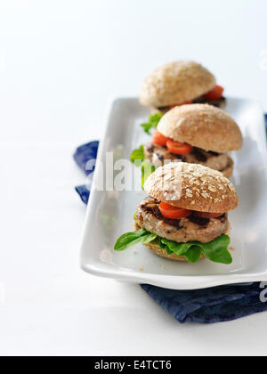 Hamburger de dinde grillé sliders de pains de blé entier avec de la tomate et laitue sur plateau avec serviette en tissu bleu Banque D'Images