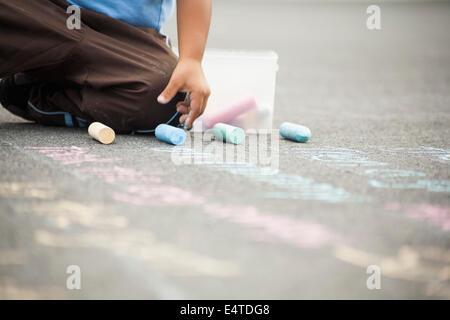 Boy Drawing on Sidewalk with Chalk Banque D'Images