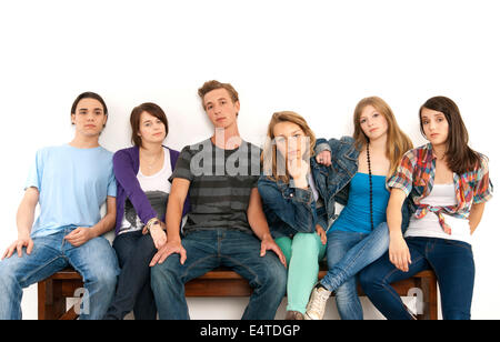 Portrait de six jeunes gens assis ensemble sur un banc, studio shot on white background Banque D'Images