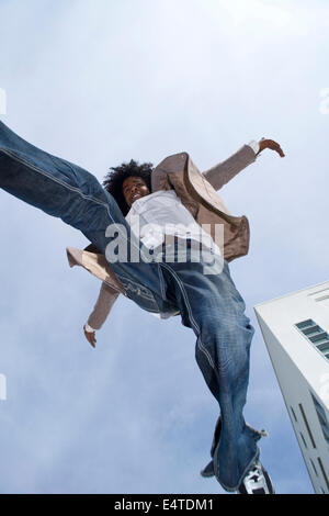 Jeune homme à l'extérieur, sauter dans les airs contre ciel, Mannheim, Allemagne Banque D'Images