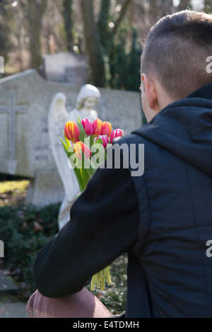 Adolescent en face de pierres tombales avec des tulipes dans Cemetery Banque D'Images