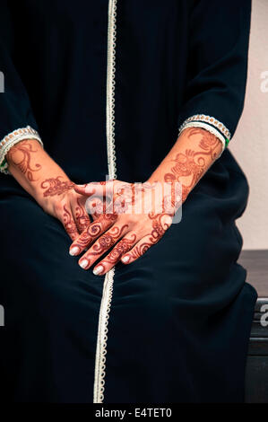 Femme assise avec close-up des bras et des mains peints avec le henné en style arabe, vêtu de noir, arabe, musulman dress Banque D'Images