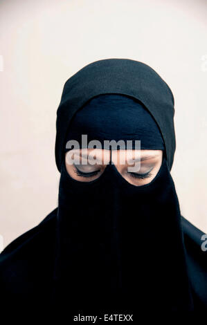 Portrait of young woman in black, musulmans et musulmanes hijab robe, les yeux fermés avec le maquillage des yeux, studio shot on white background Banque D'Images