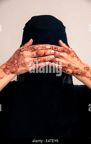 Portrait de femme en noir hijab musulman et musulmane robe, couvrant les yeux et les mains au henné peints dans un style arabe Banque D'Images