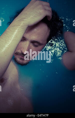La dépression, l'homme en bleu baignoire pleine d'eau, la tristesse concept Banque D'Images