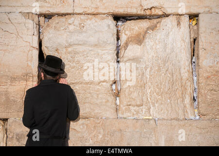 L'homme juif prie à côté d'une fissure remplie de lettres écrites contenant la prière au Mur des lamentations à Jérusalem. Israël Banque D'Images