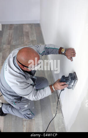 L'homme en utilisant power sander on wall Banque D'Images