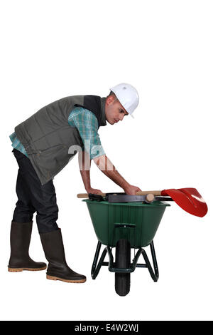 Ouvrier de placer ses outils dans une brouette Banque D'Images