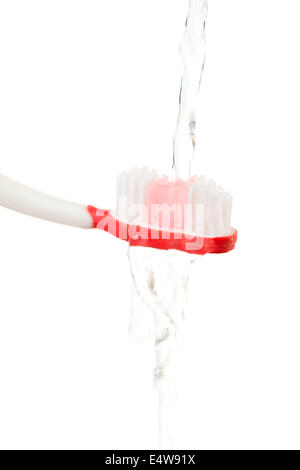 L'eau qui coule sur une brosse à dents rouge Banque D'Images