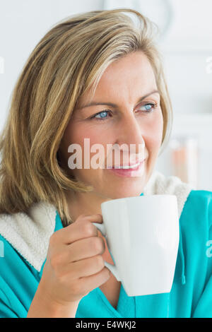 Thoughtful woman sitting in the kitchen Banque D'Images