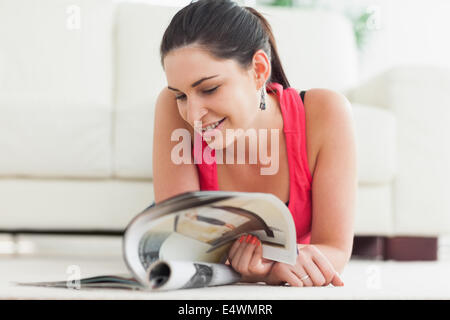 Woman lying on floor looking at catalogue Banque D'Images