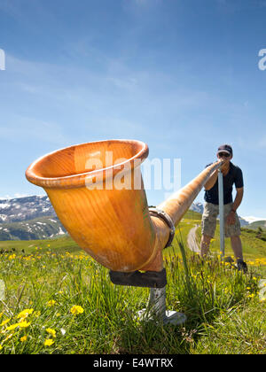 Low angle de vue d'un homme jouant un cor des alpes dans les Alpes Suisses Banque D'Images