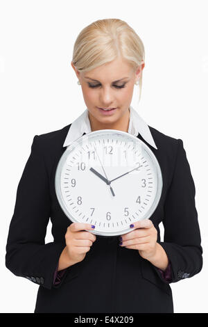 Smiling blonde in suit holding a clock Banque D'Images